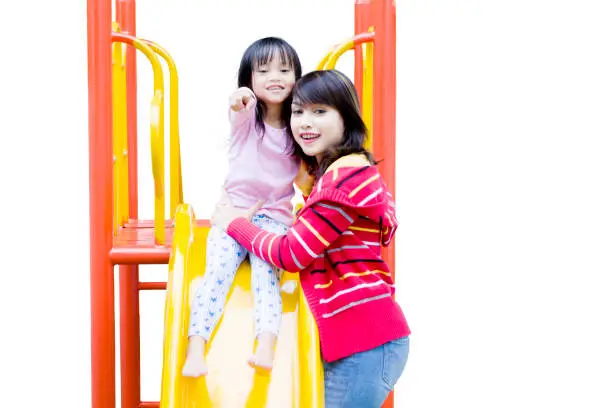 Pretty mother with her daughter playing in the playground while pointing at the camera, isolated on white background
