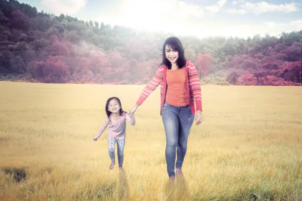 Picture of a pretty woman walking with her daughter in the meadow. Shot at autumn time