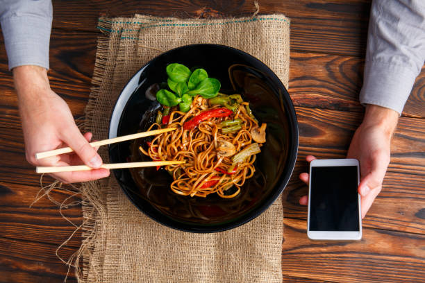 istock A man's hand using chopsticks and a telephone. Close-up. 861139742