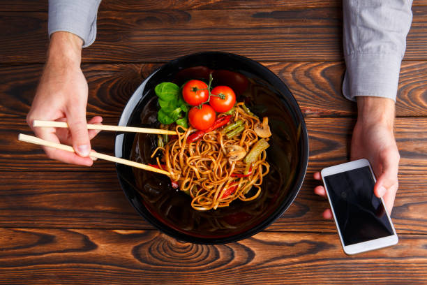 istock A man's hand using chopsticks and a telephone. Close-up. 861139788
