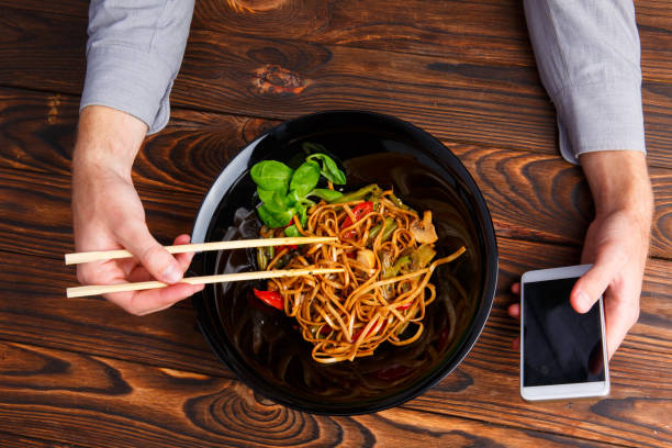 istock A man's hand using chopsticks and a telephone. Close-up. 861139832