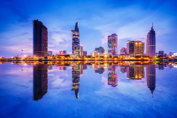 Reflection of Night view of Business District and Administrative Center of Ho Chi Minh city on Saigon riverbank. Ho Chi Minh city (aka Saigon) is the biggest city and economic center in Vietnam with population around 10 million people. It is also a popular tourist destination of Asia.