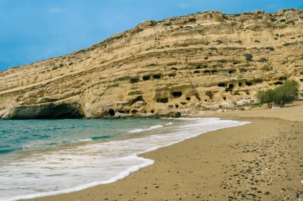 view of the famous beach of Matala with the impressive formations of sandstone rock cliffs with their worldwide known caves where hippies of 60’s and 70's were living in