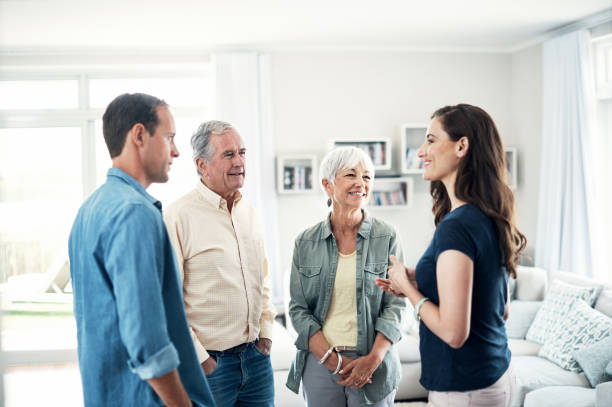 Please stay a little longer... Shot of a young couple and their elderly parent spending some time together at home father in law stock pictures, royalty-free photos & images