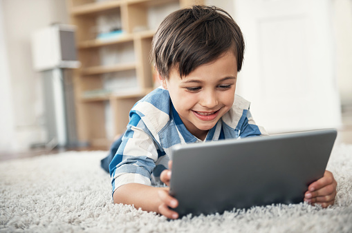 Shot of a cute little boy using a digital tablet at home