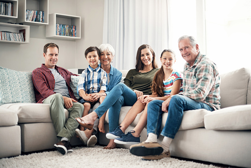 Shot of a three-generational family sitting together on a sofa at home