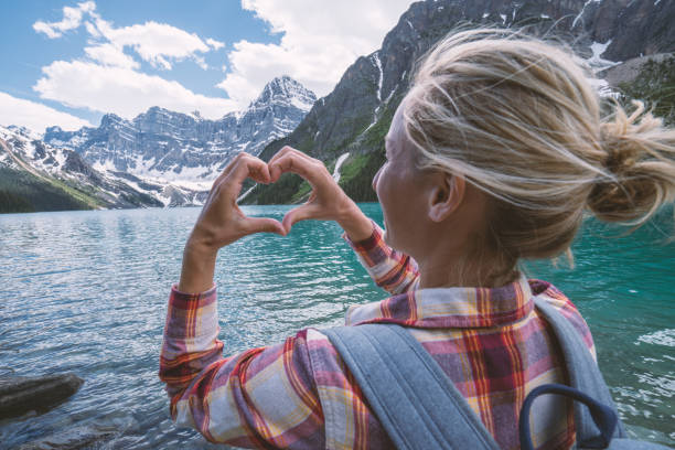 istock Young woman making heart shape finger frame on mountain lake 861168820