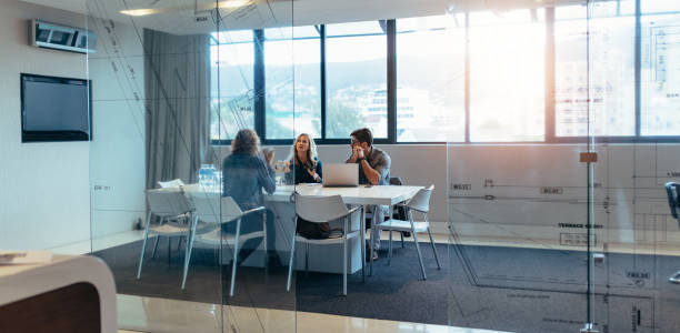 Three designers discussing in meeting hall Three designers discussing about new project in meeting hall. Group of executives meeting in boardroom. architect office stock pictures, royalty-free photos & images