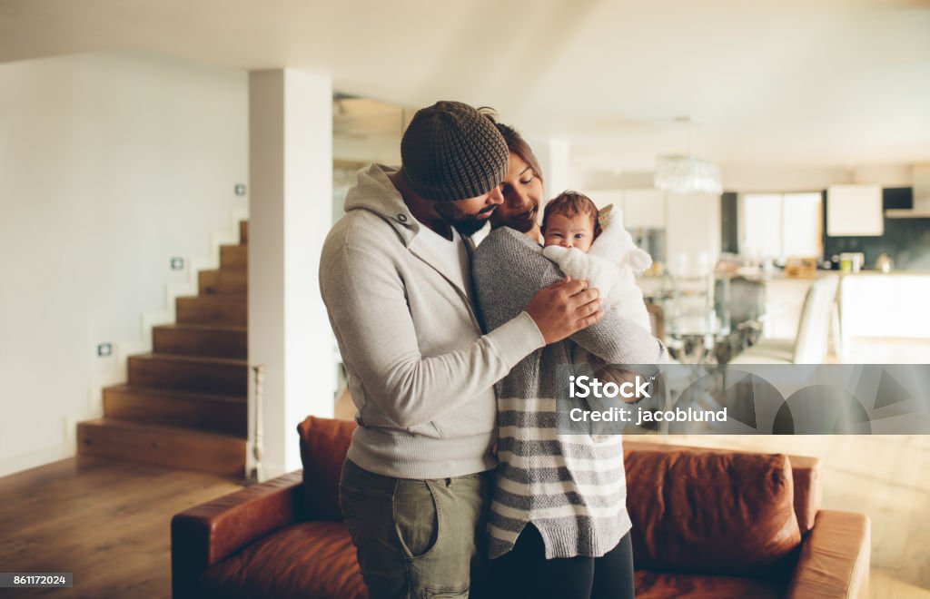 Young father and mother holding their baby boy Young father and mother holding their baby boy. Parents spending time with newborn son at home in the living room. Newborn Stock Photo