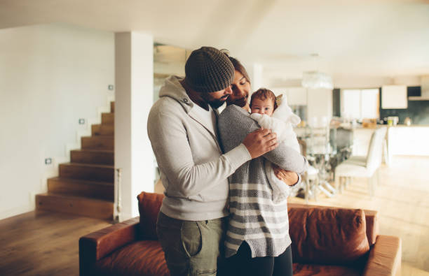 Young father and mother holding their baby boy Young father and mother holding their baby boy. Parents spending time with newborn son at home in the living room. biracial newborn stock pictures, royalty-free photos & images
