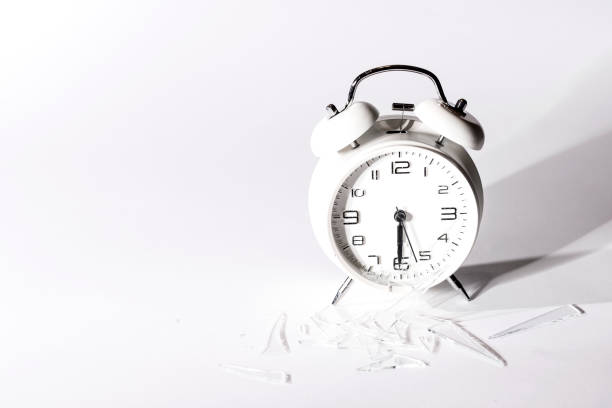 istock White crashed alarm clock and shards of glass on white background. 861172590