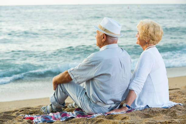 istock female and male in hat sitting on the beach 861177800