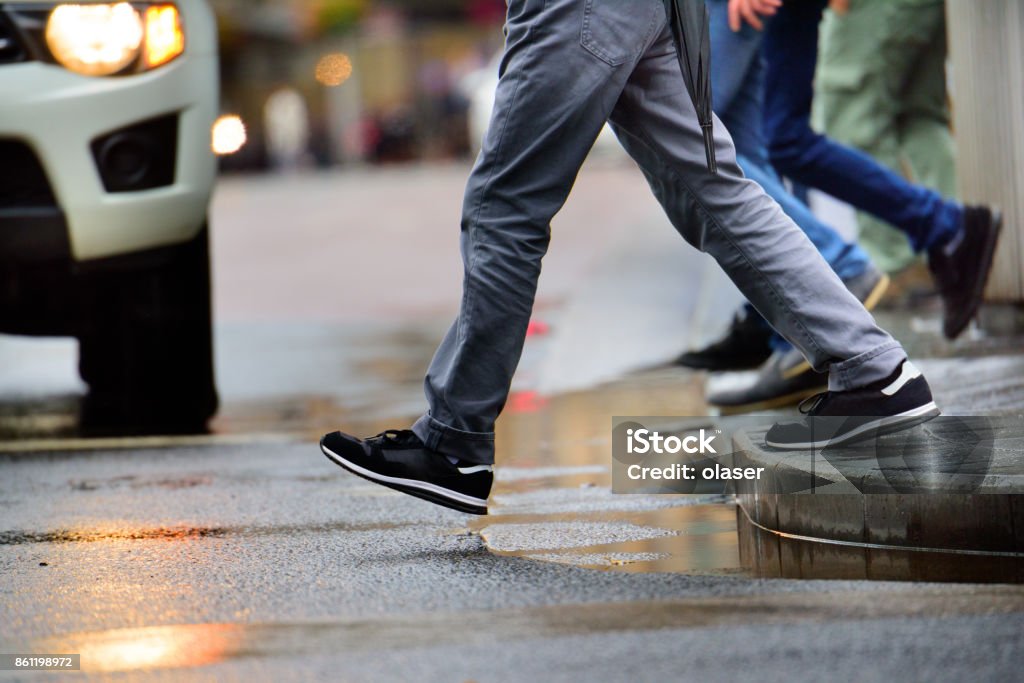 Man stepping over puddle in rain Man stepping over puddle in rain

 Pedestrian Stock Photo