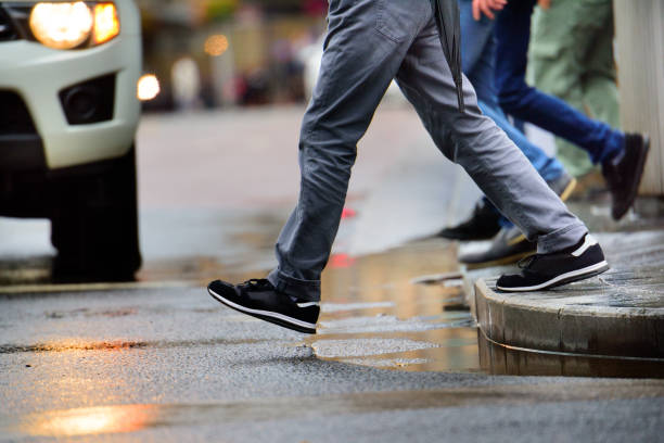 człowiek stepping nad kałużą w deszczu - pedestrian zdjęcia i obrazy z banku zdjęć