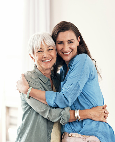 Portrait of a young woman and her older mother in a warm embrace at home