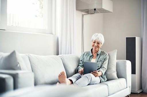 Shot of a senior woman relaxing on the sofa and using a digital tablet