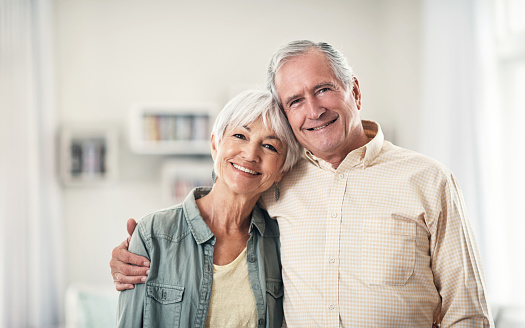 Portrait of a happy elderly couple standing together in their home