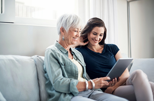 Shot of a happy senior woman and her daughter relaxing on the sofa and using a digital tablet together