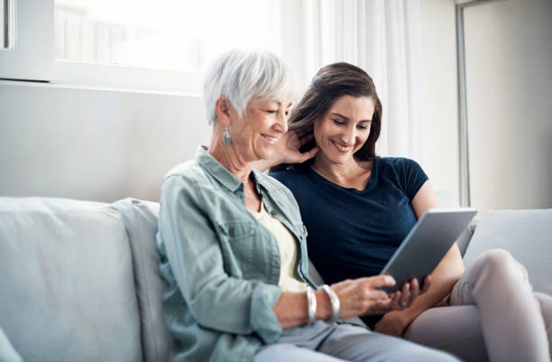 enhancing mother daughter time with online entertainment - ipad senior adult facebook sofa imagens e fotografias de stock