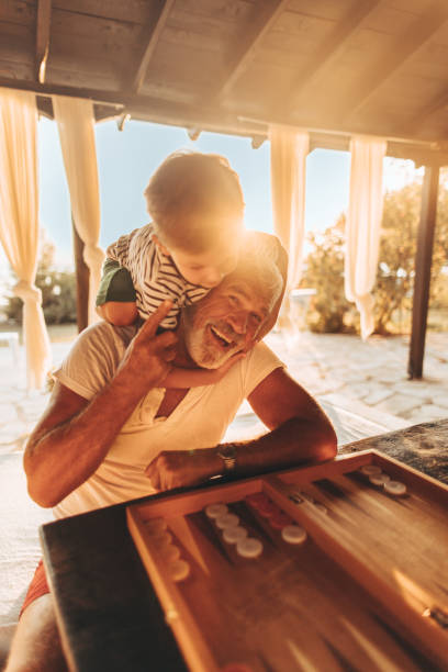 Playing backgammon with my grandson Photo of a little boy playing board games with his grandfather on a terrace of a family home at sunset backgammon stock pictures, royalty-free photos & images