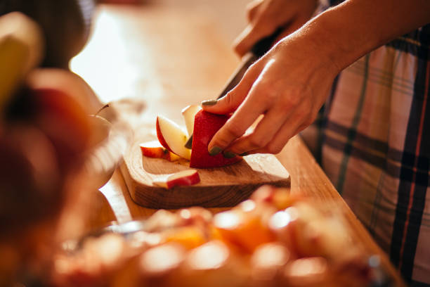 junge frau hände schneiden einen apfel auf holz geschnitten board - fruit salad fruit healthy eating making stock-fotos und bilder