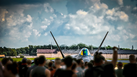 A crowd watches a jet warming up and preparing for take off.