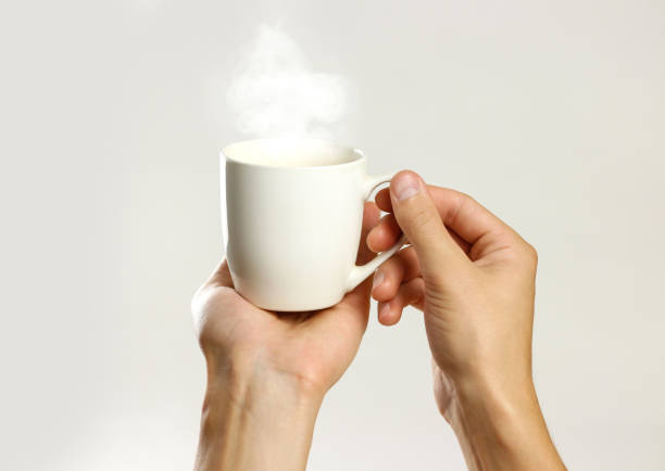 istock Male hand holding white empty glass mug. Isolated on gray background. Closeup. 861226108