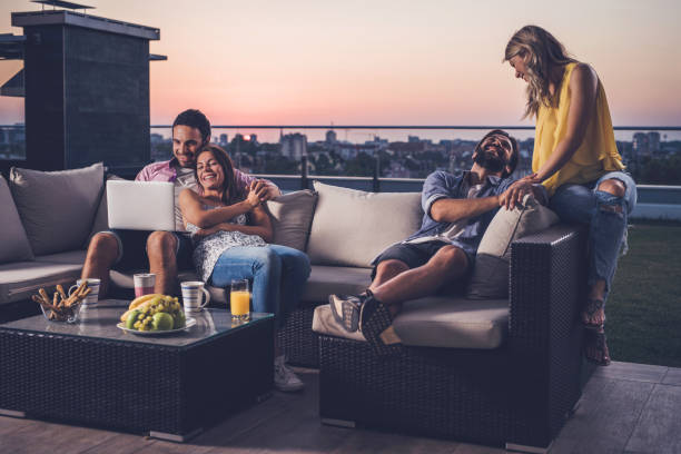 istock Two happy couples relaxing on sofa at penthouse balcony. 861229906