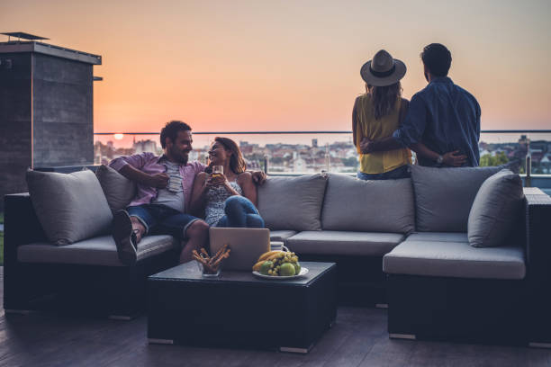 Young couples relaxing on a penthouse patio at sunrise.