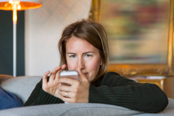 istock Young Woman using her Smartphone while Relaxing on the Couch at Home 861233058