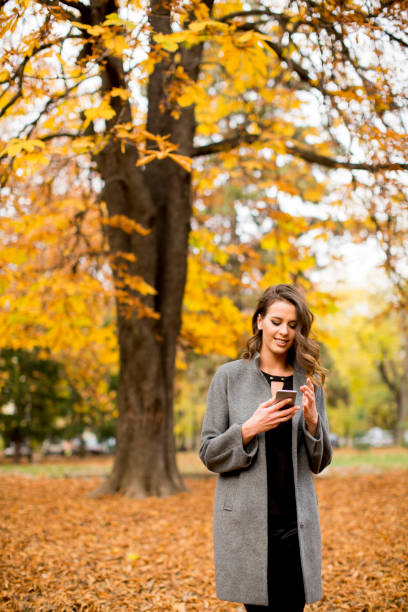 istock Young womanusing mobile phone in autumn park 861233526