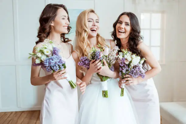 beautiful laughing bride with bridesmaids holding bouquets