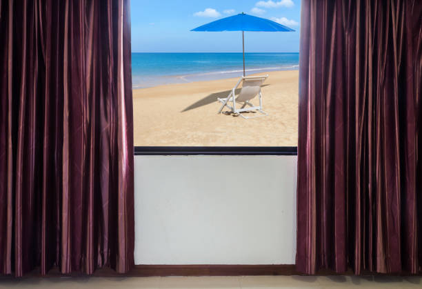 istock window with curtains and blinds looking out the window frame meet seaside view with white wooden beach chair and blue parasol 861251496