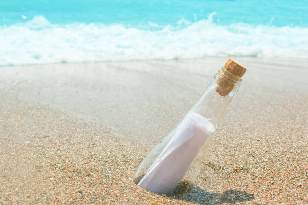 istock Message in a glass bottle on the sand. Sea and waves. A note on salvation, please help 861260504