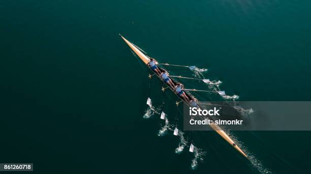 Four Male Athletes Sculling On Lake In Sunshine Stock Photo - Download Image Now - Teamwork, Sport Rowing, Rowing