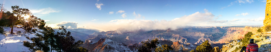 Panoramic view of man staring over the the South Rim of the Grand Canyon, Arizona, USA