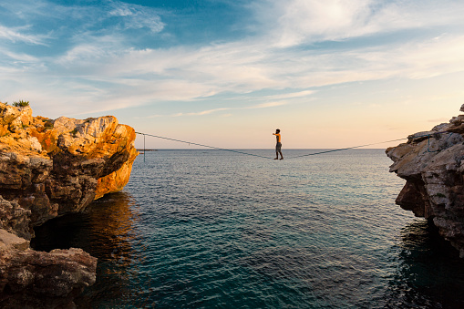 Man practicing slackline over the sea in Minorca Balearic Islands Spain