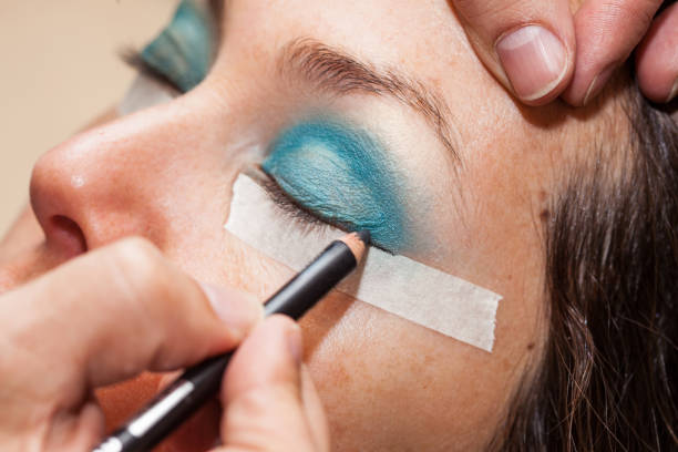 Close up of a make up artist using masking tape to create cat eyes