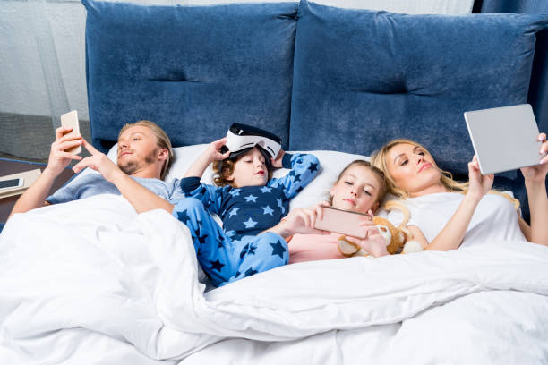 istock family with gadgets in bed 861283266