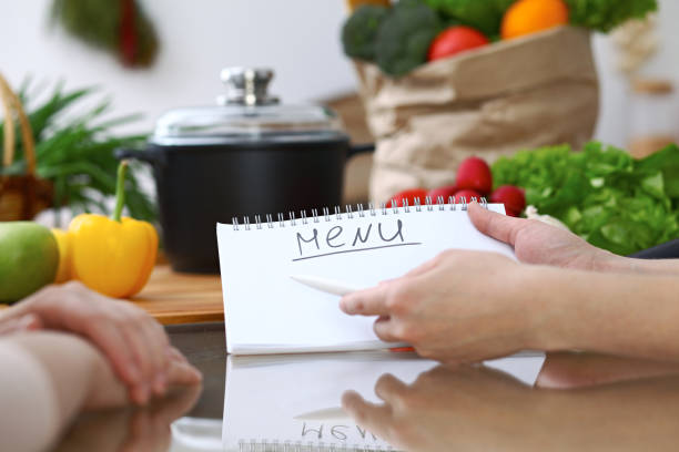 istock Close-up of human hands pointing into note book copy space area in the kitchen.  So much ideas for tasty cooking. Vegetarian, healthy meal and friendship concept 861286720