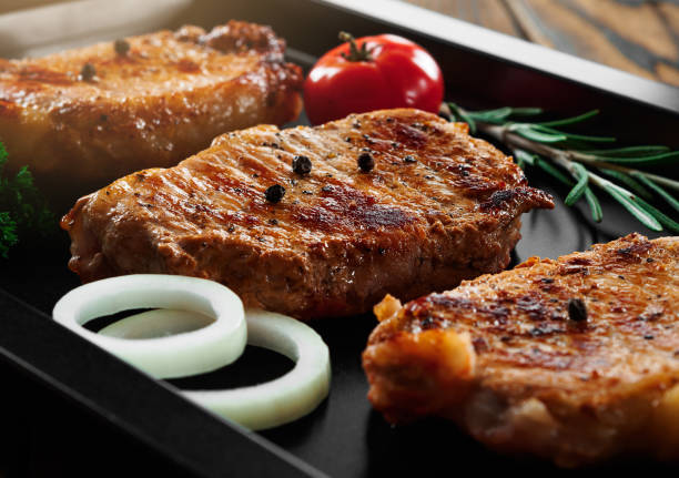 istock Baked pork steaks on a black baking sheet on wooden background 861295678