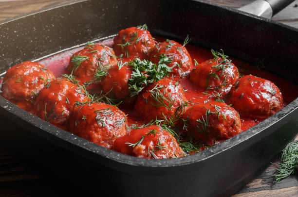 Meatballs with spicy tomato sauce in pan. on wooden background stock photo
