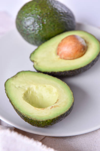 avocado maturo fresco su un piatto. - avocado cross section vegetable seed foto e immagini stock