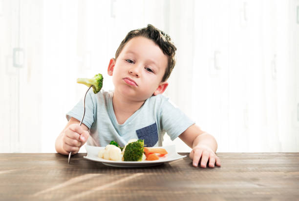 dziecko jest bardzo niezadowolone z konieczności jedzenia warzyw. - cute disgust carrot caucasian zdjęcia i obrazy z banku zdjęć