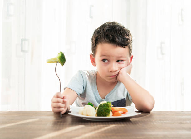 子供が野菜を食べることに非常に満足ではないです。 - cute disgust carrot caucasian ストックフォトと画像