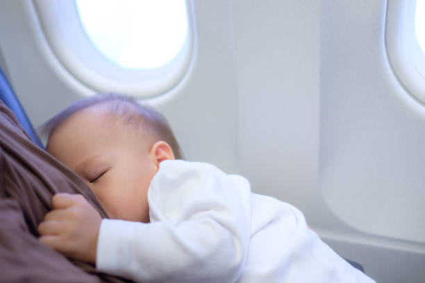 Asian mother is breastfeeding Cute little Asian 18 months toddler baby boy child on Airplane stock photo