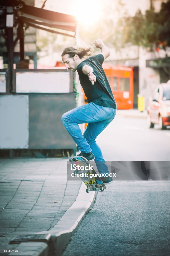 Pro skater doing tricks and jumps on street. Free ride Pro skater riding skate, doing tricks and jumps on the main streets through cars and urban traffic. Free ride skateboard Active Lifestyle Stock Photo