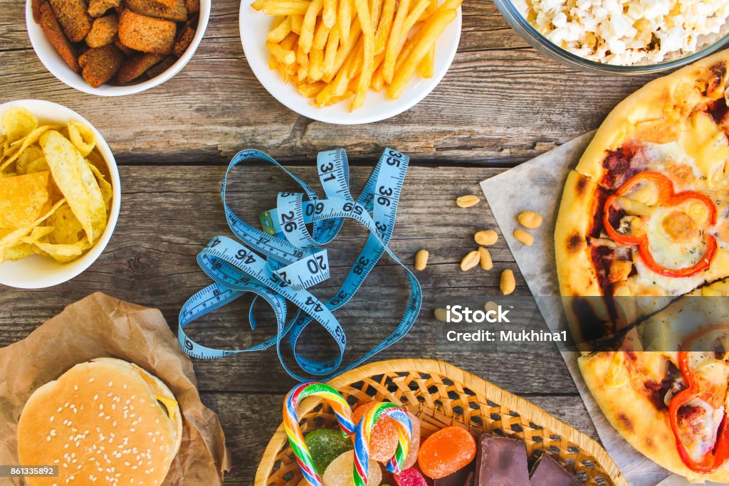 Fast food, tape measure on old wooden background. Concept of junk eating. Toned image. Top view. Fast Food Restaurant Stock Photo