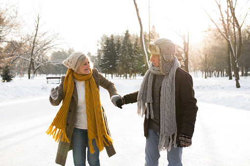 Beautiful senior woman and man in sunny winter nature on a walk.