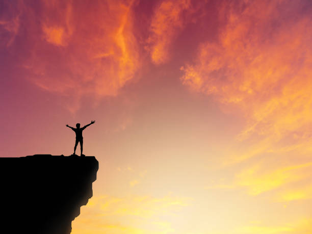 istock Silhouette man standing on mountain cliff sunset background 861340944